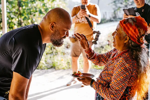 A host placing a traditional red tika blessing on a trekker's forehead