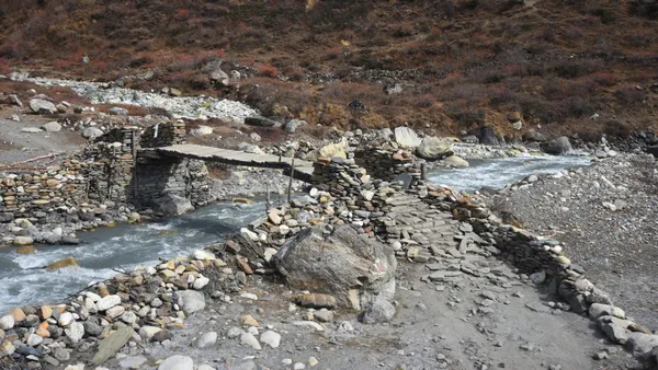 A rustic wooden and stone bridge spanning a mountain stream