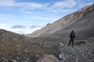 A trekker on barren scree above the clouds