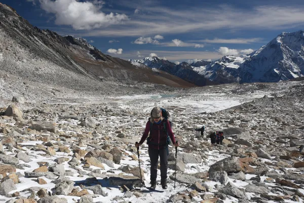 A hiker picking their way across rocky terrain with walking poles
