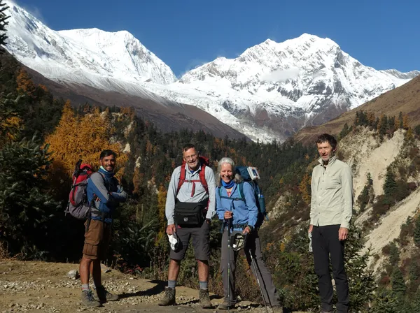 A group of trekkers posing against a backdrop of massive snow-covered peaks