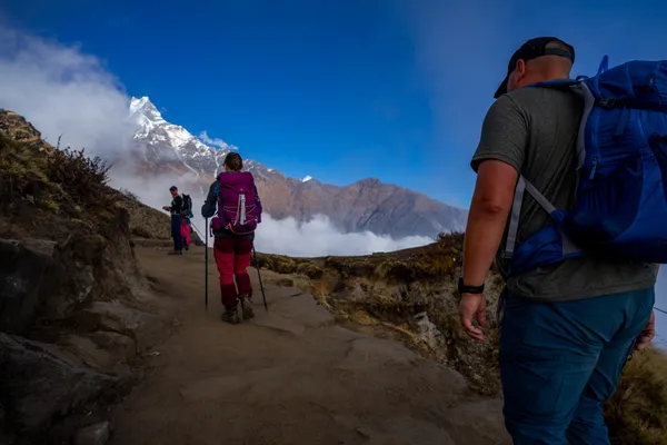 Hikers following the exposed ridgeline trail above a sea of clouds