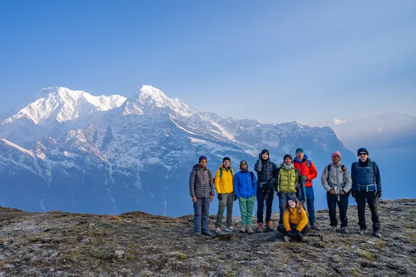 The group pausing for a photo on the grassy ridgeline with Himalayan views