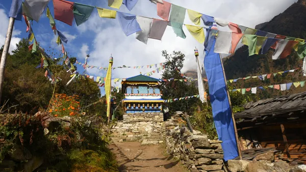 A colorful Buddhist chorten and strings of prayer flags marking a village entrance