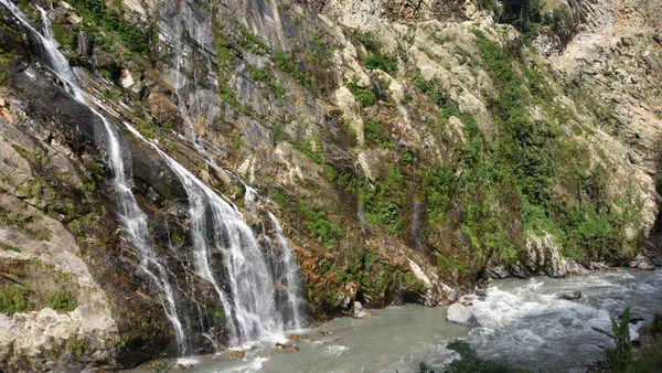 Mountain water cascading down a rock face into a river