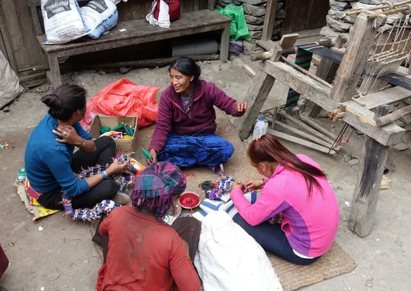 Local women weaving colorful textiles by hand outside their homes in Ghap