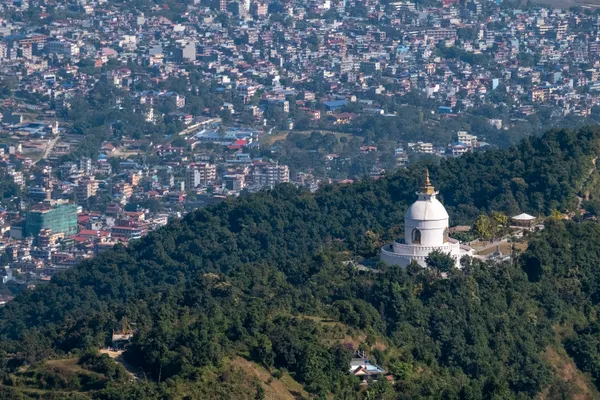 The gleaming white World Peace Pagoda crowning a forested hilltop above Phewa Lake